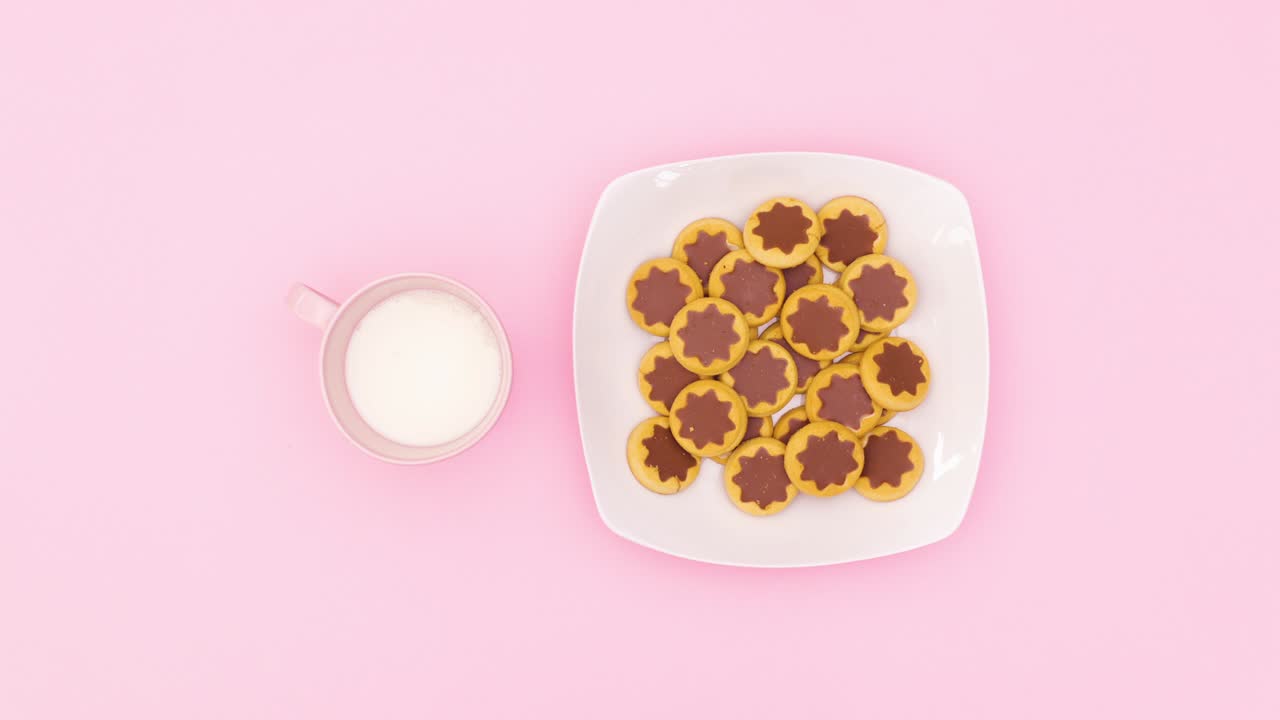 쿠키는 색 접시와 우유를 채우는 분홍색 컵에서 분홍색 테마로 나타납니다. 움직임을 멈추십시오.