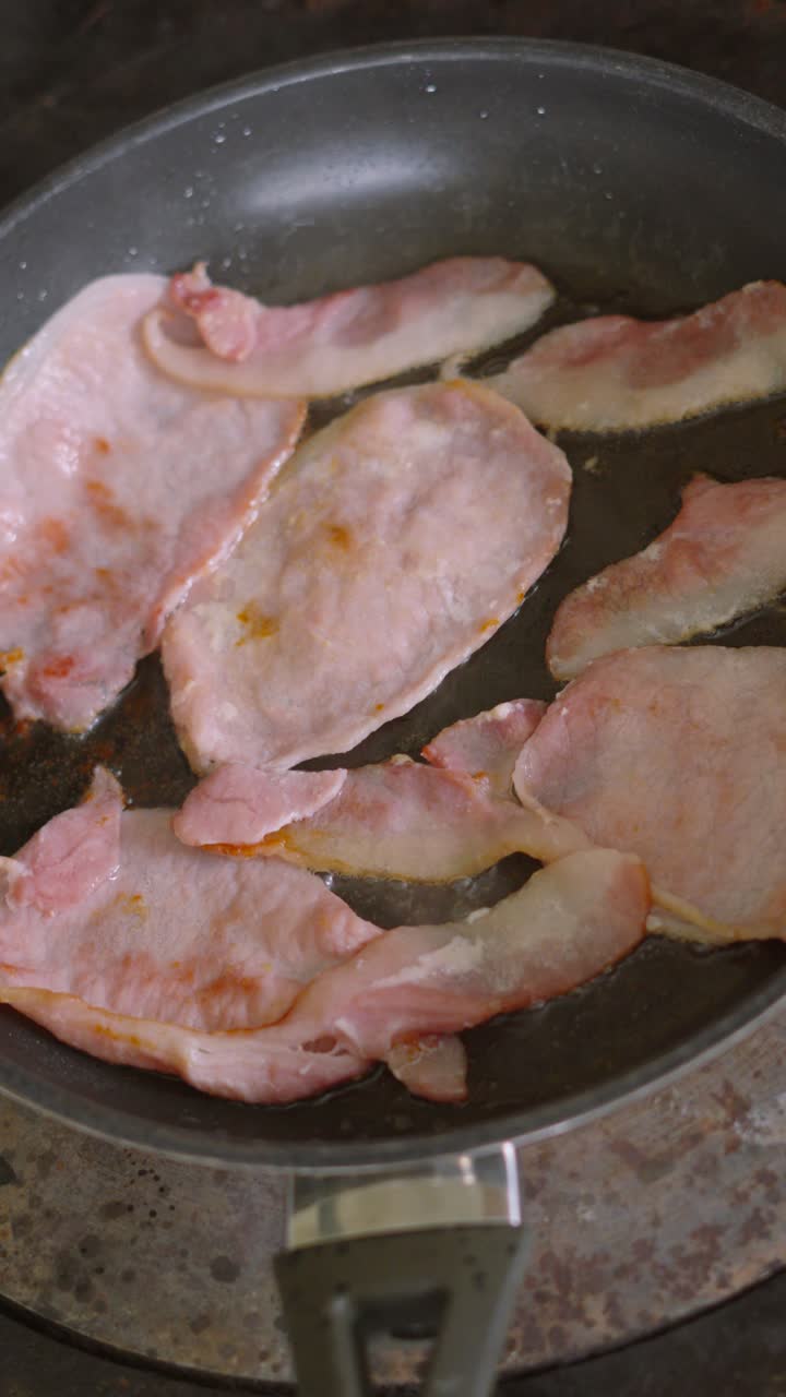 Vertical Video of Delicious Smoked Bacon Slices Cooking in Hot Pan with Bubbling Oil on Stove. Breakfast Morning Food.