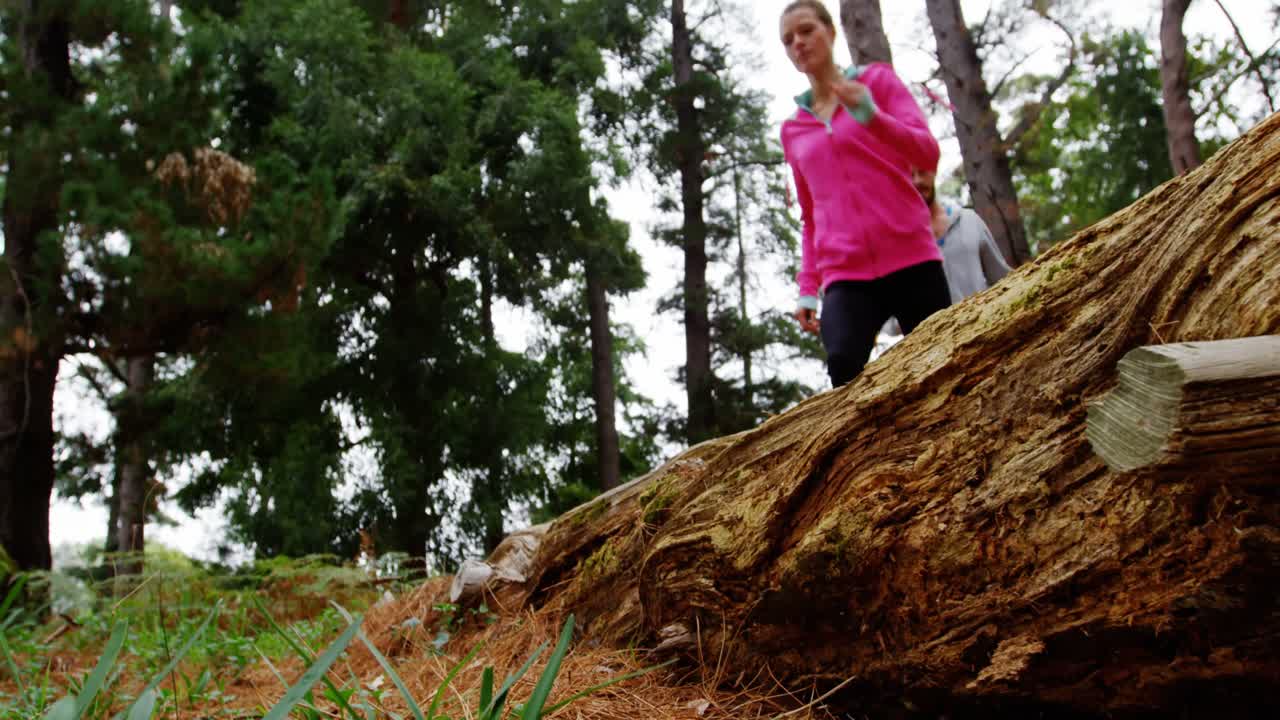 pareja saltando sobre un tronco de árbol