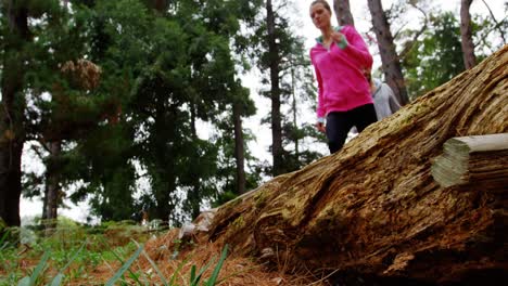 couple jumping over a tree trunk