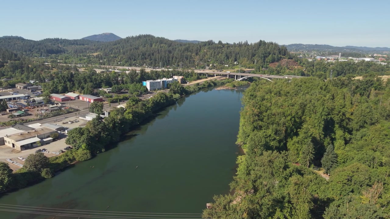 Filmato drone del fiume Willamette a Eugene, Oregon, che si muove lateralmente sopra la riva del fiume prima di rivelare il fiume calmo in una limpida giornata estiva