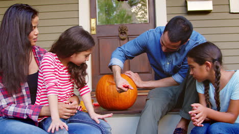 familia tallando calabaza de halloween en los escalones de la casa