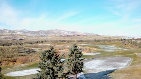 parallax shot of a golf course in winter with a light dusting of snow - zooming in during retreating dolly move