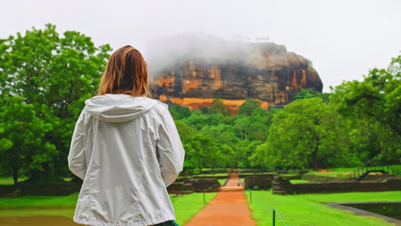 스리랑카의 시기리아 또는 라이온스 록 (lions rock) 으로 향하는 빈 길에서 느린 속도로 고 있는 젊은 관광 여성의 뒷면