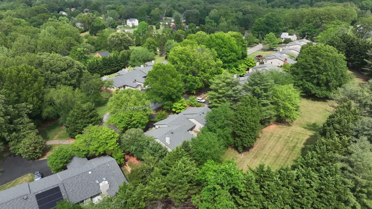 Modern houses with grey roof between green forest trees in summer. Aerial top down flyover shot. Quiet suburb neighborhood of Pennsylvania, USA