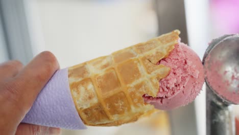 cuchara de helado de fresa de video vertical en cono de galleta, primer plano, en órbita