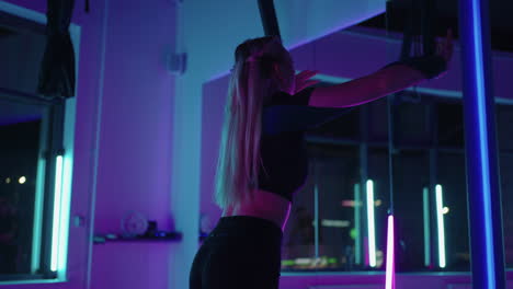 Eine-Frau-Macht-Sportyoga-In-Der-Luft-Auf-Einer-Hängematte-Im-Neonlicht-Und-Führt-Anmutige-Übungen-Und-Bewegungen-Aus-Dehnübungen-Und-Tanzen-In-Zeitlupe-Aus.