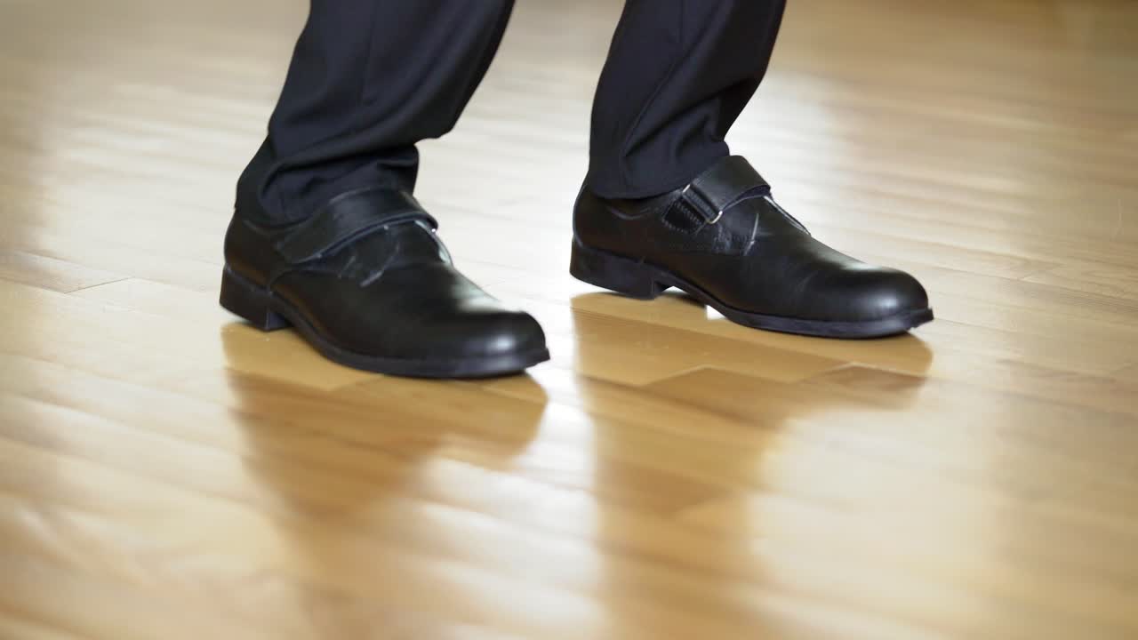 funny man in black shoes and trousers is dancing on a brown laminate