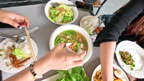 hands preparing and enjoying traditional lao dishes in a vibrant setting. bright lighting enhances the colorful and inviting atmosphere