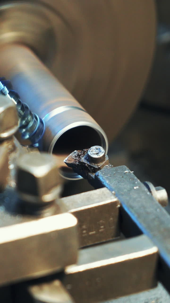 A metal part rotates and sharpeners on the lathe in the workshop in the manufacturing. Close-up. Vertical video