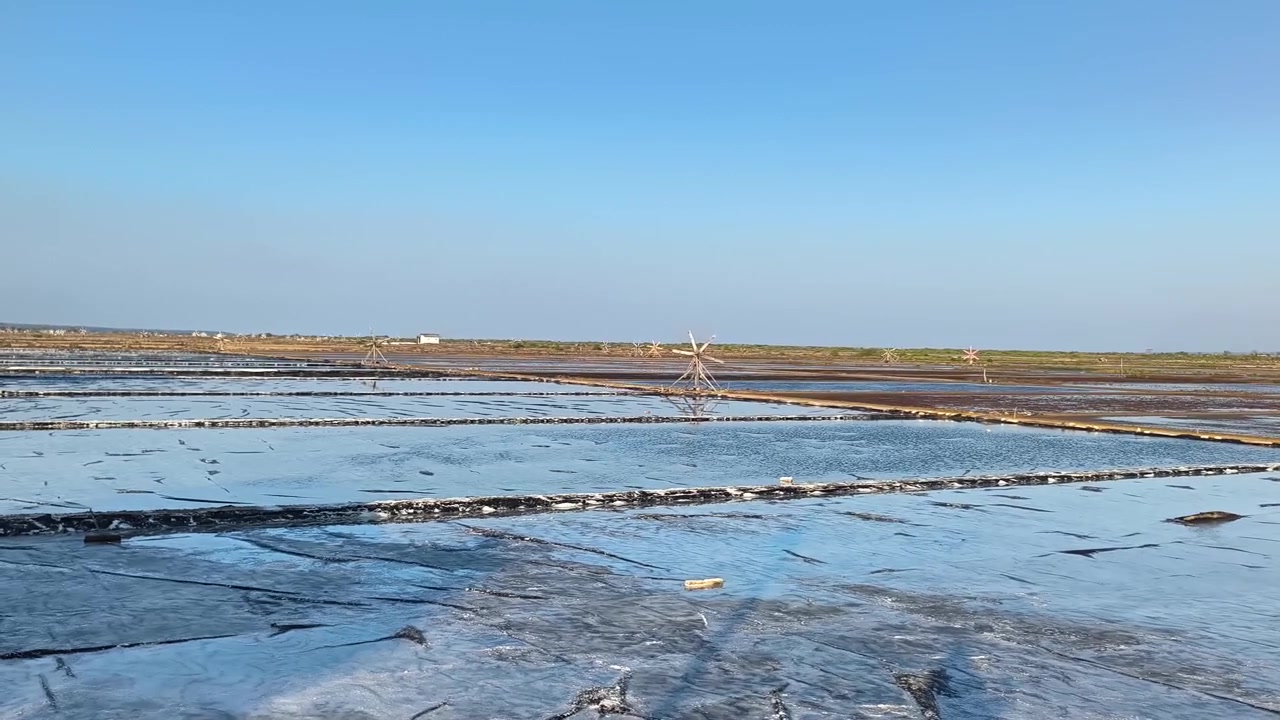 Traditional Salt Pans with Wooden Windmills Under Clear Blue Sky