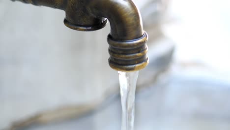 antique bronze water tap with flowing water