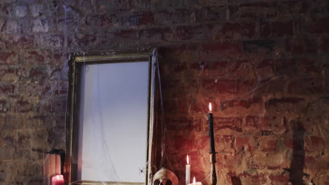 video de una pila de libros, marco con tela de araña, cráneo y velas en el fondo de la pared de ladrillo