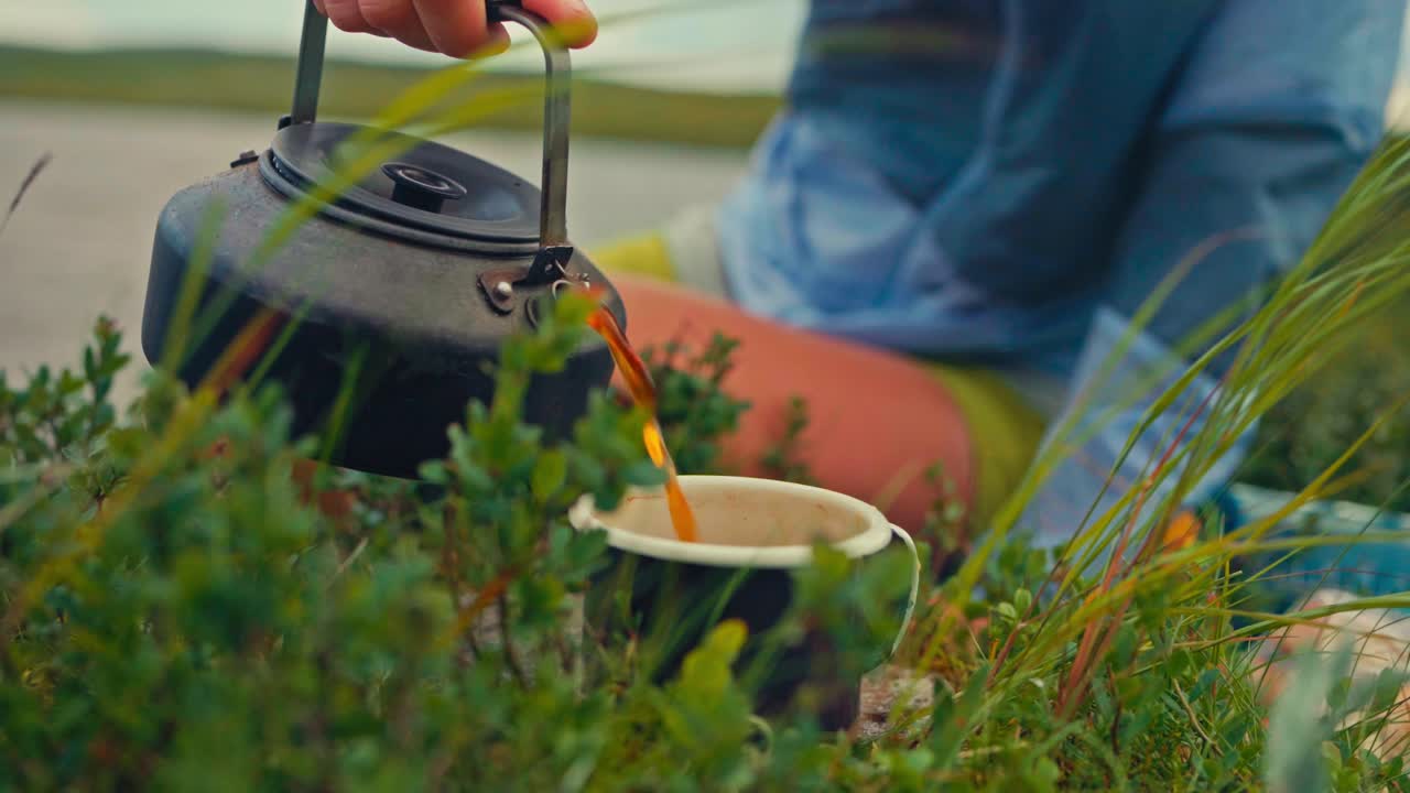 Hand Pouring Hot Tea In A Cup During Outdoor Camping - Close Up