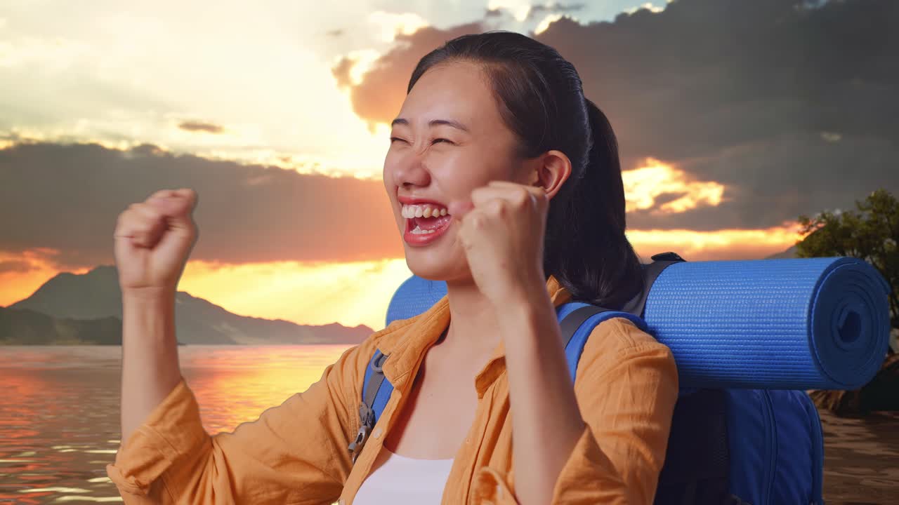Close Up Side View Of Asian Female Hiker With Mountaineering Backpack Screaming Goal Celebrating The Success While Standing At A Lake During Sunset Time