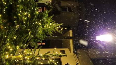 Grüner-Weihnachtsbaum-Mit-Leuchtenden-Lichtern-Bei-Schneefall-In-Der-Stadt-Kaunas,-Vertikales-Video