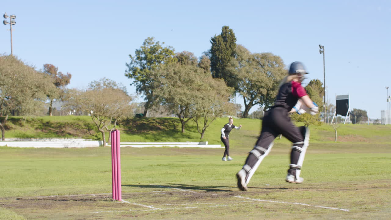 Playing cricket, woman preparing to bowl on outdoor field, enjoying sunny day