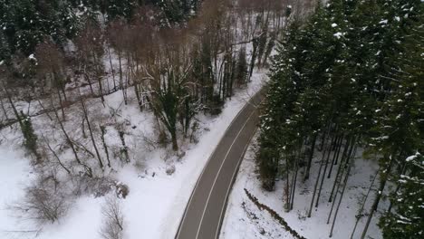 Vista-Aérea-De-La-Carretera-Rural-De-Invierno-En-El-Bosque-Nevado