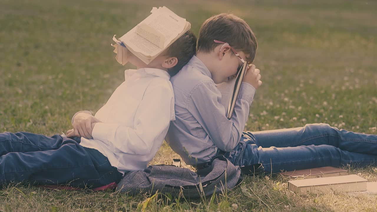 지친 어린 학교 동료 들 은 얼굴 에 책 을  ⁇ 고 잠 을 자고 있다