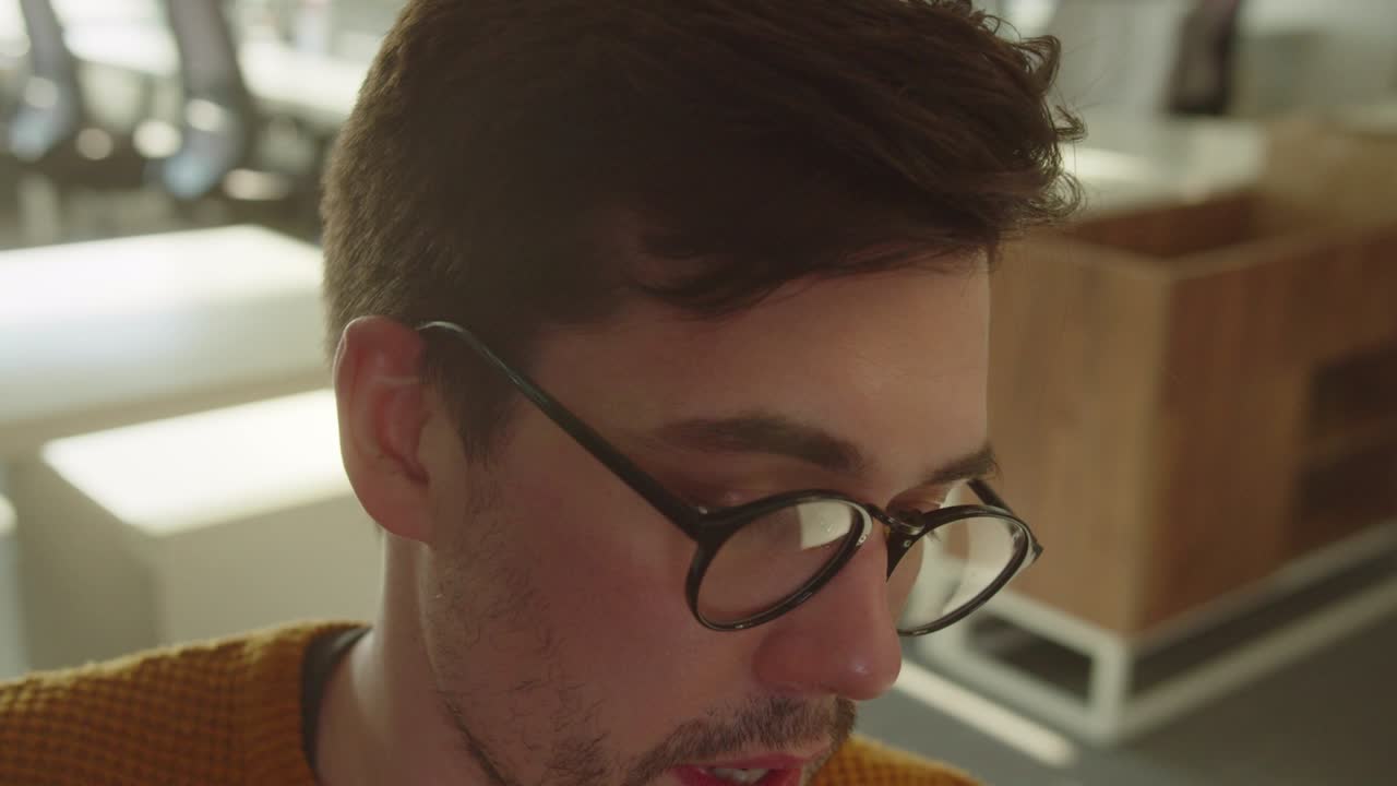 sentado en la zona de descanso en la universidad, un joven estudiante está hablando con su amigo y sonriendo, cámara lenta de cerca