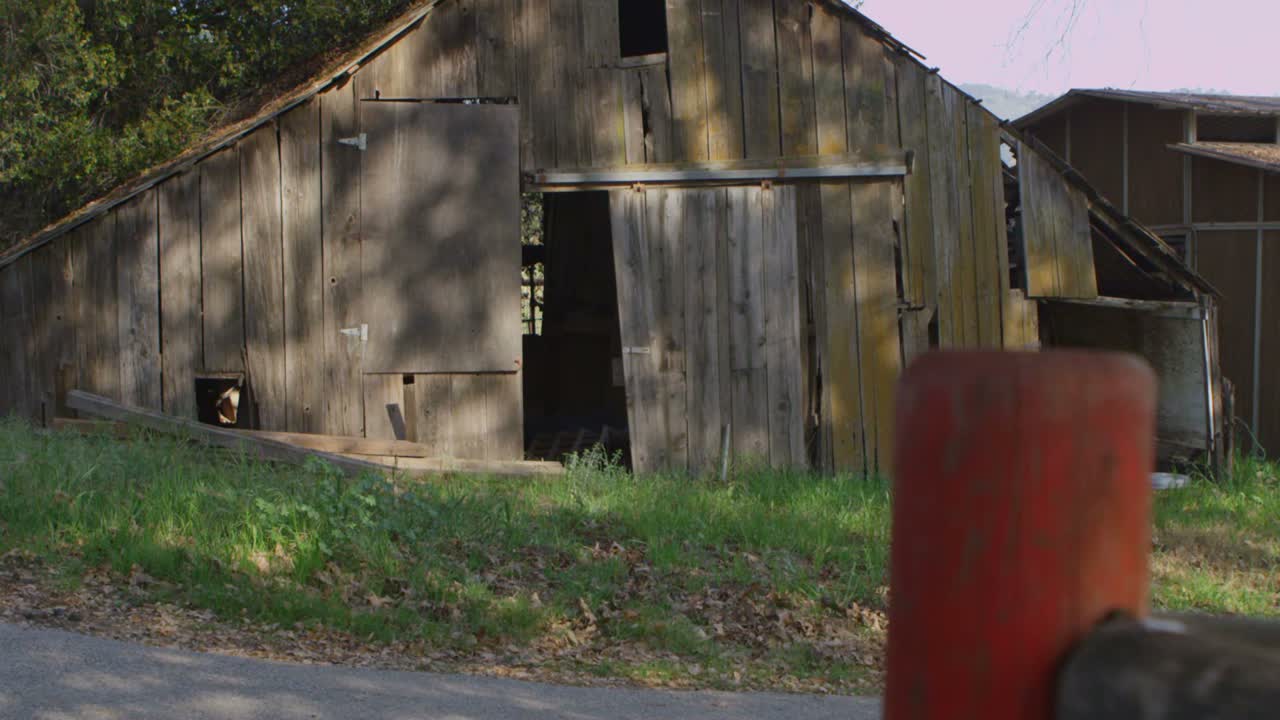 una vieja camioneta se detiene frente a un antiguo granero