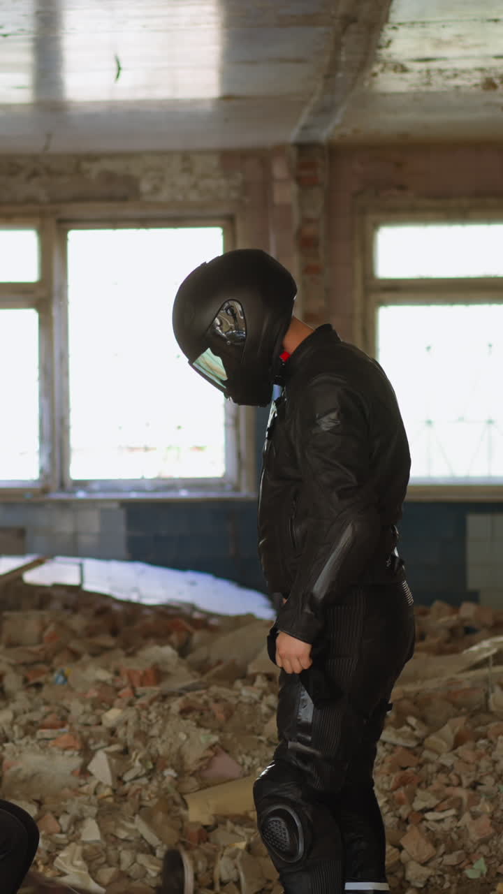 Man in moto suit and hardhat stabs criminal to protect young woman victim with green bag on head in abandoned building side view slow motion