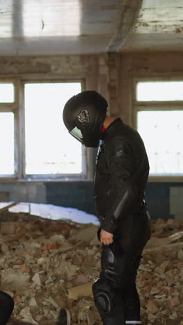 man in moto suit and hardhat stabs criminal to protect young woman victim with green bag on head in abandoned building side view slow motion