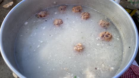 Popular-fast-food-of-Hong-Kong,-many-fish-balls-boil-at-soupy-broth,-close-up-shot-of-large-pan-in-China-town,-Kolkata,-India