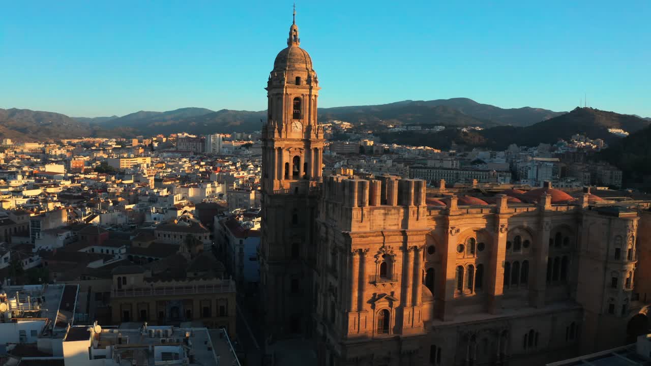 Drone panoramico aereo dell'architettura della Cattedrale di Malaga in Spagna, punto di riferimento religioso della città, cristianesimo, colline e sfondo dello skyline al tramonto.