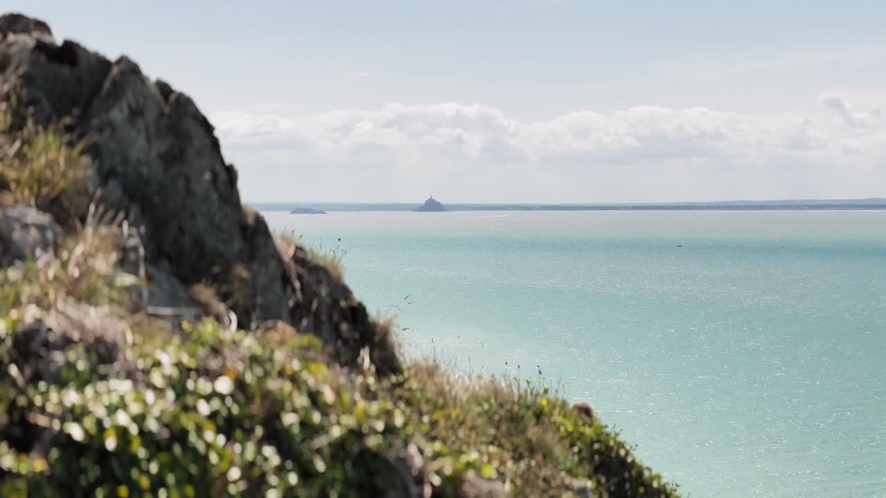 Scenic footage captures a breathtaking view of Mont Saint-Michel as seen from the cliffs of Carolles in Normandy. Perched high above the coastline
