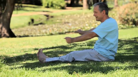 hombre anciano calentándose sentado en la hierba
