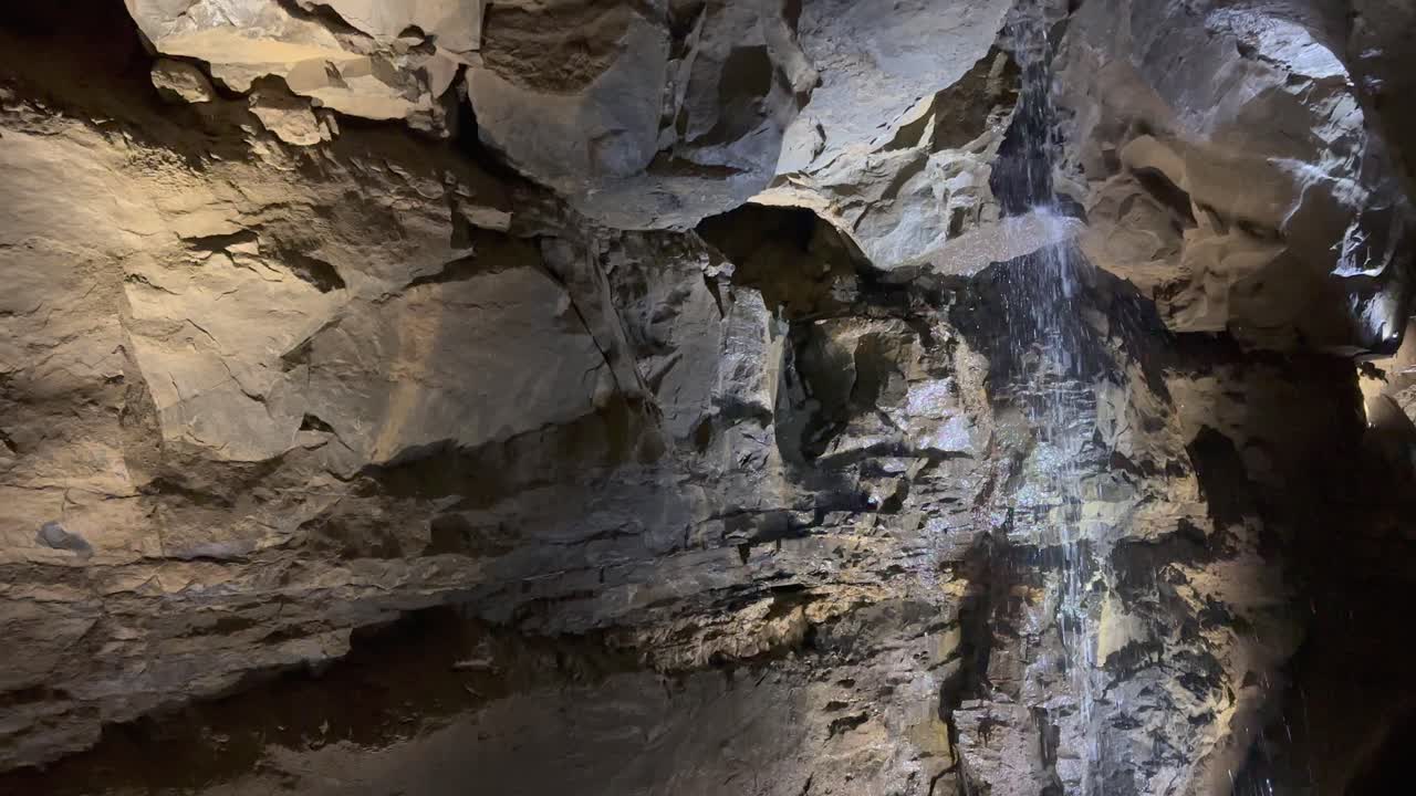 fondo de la naturaleza de la cueva: una pequeña cascada gotea por la pared de la caverna