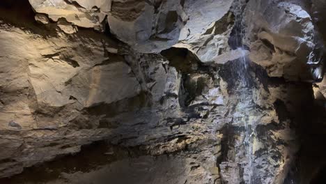 Cave-nature-background:-Small-waterfall-trickles-down-wall-of-cavern