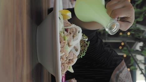 Pouring dressing on a fresh tuna salad