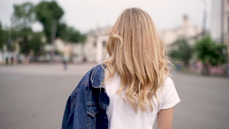 Mujer-Joven-Feliz-Sonriendo,-Mirando-Hacia-Atrás-Y-Caminando-Por-La-Calle