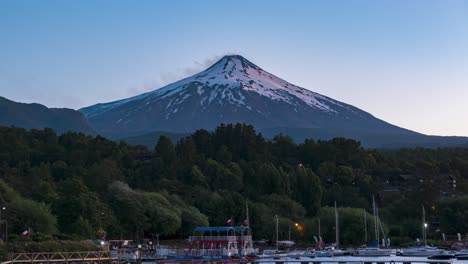 timelapse of sailing boats in docks surrounded by woods and active villarrica volcano at golden hour, la poza, pucon, chile