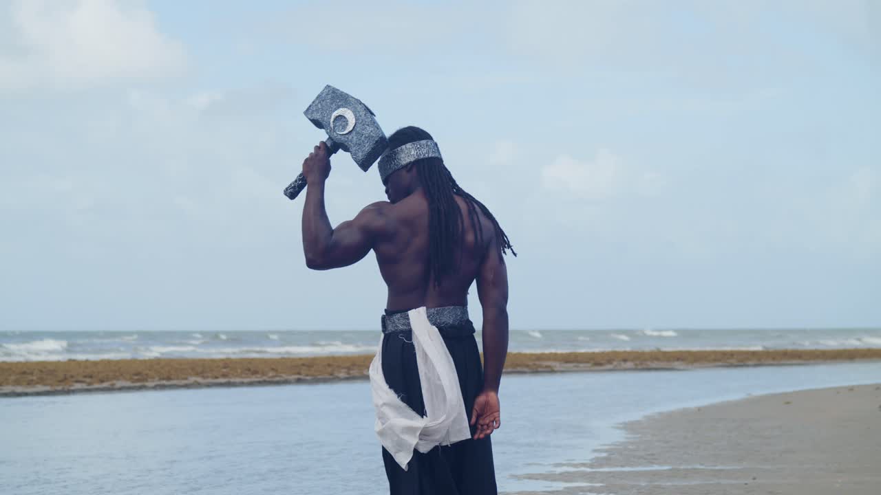 The tropical beach provides the ideal setting for a muscular, dark-skinned man as Nekharis in cosplay