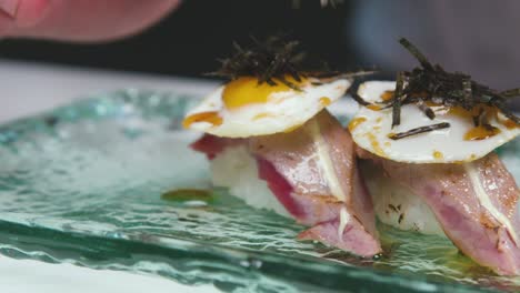 cocinero agregando algas marinas al nigiri sushi mientras prepara un plato sabroso en un restaurante moderno de comida asiática