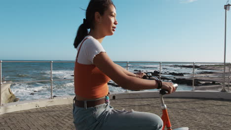 side view of a mixed race girl riding a bike seaside