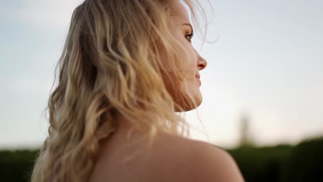 una chica rubia bonita mirando en la distancia durante la puesta de sol de la hora dorada