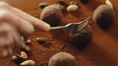 un confitero de primer plano cortando a mano chocolate de trufa con un tenedor en cámara lenta.