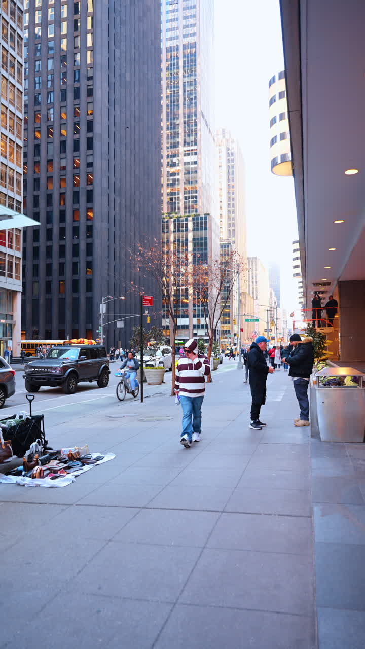 New York, USA, 18 dicembre 2025: Camminando sul marciapiede lungo le vetrine e i venditori ambulanti. Vista dal basso sui grattacieli di New York, USA. Video verticale.