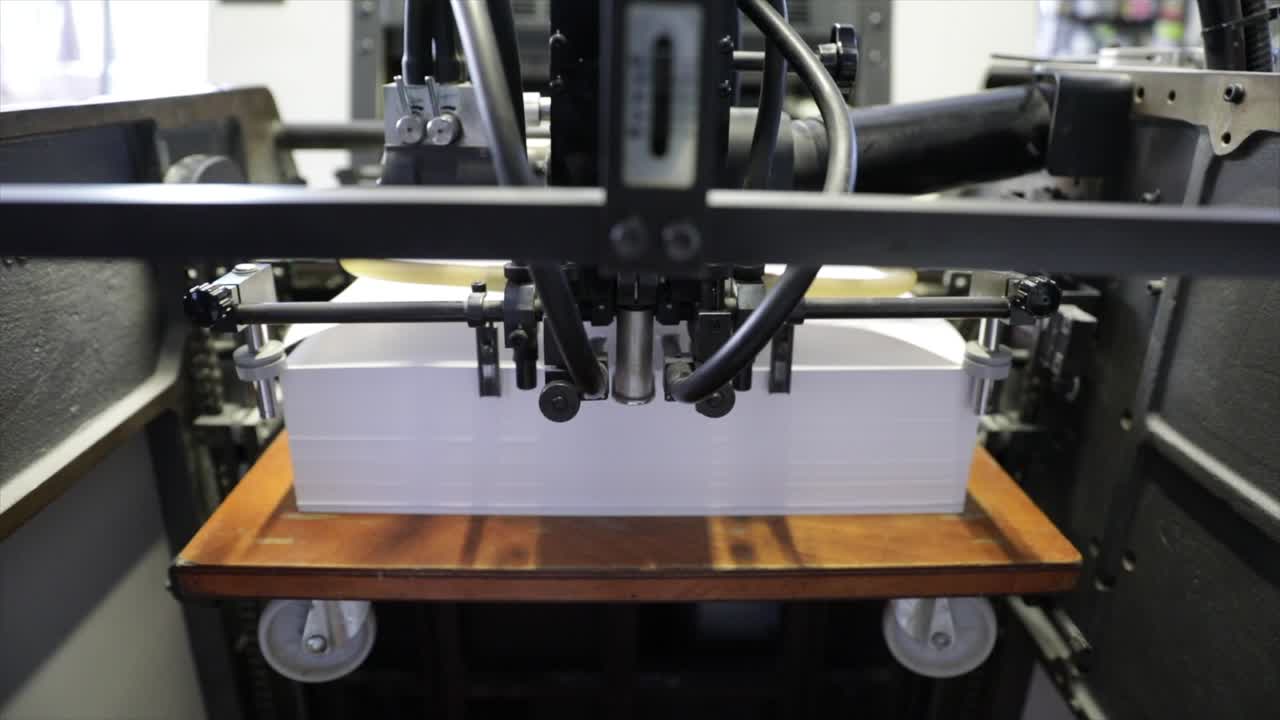 Industrial printer uploads white sheets of paper, close up view