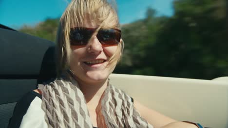 A-woman-in-sunglasses-rides-in-a-car-on-a-mountain-road