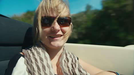 a woman in sunglasses rides in a car on a mountain road