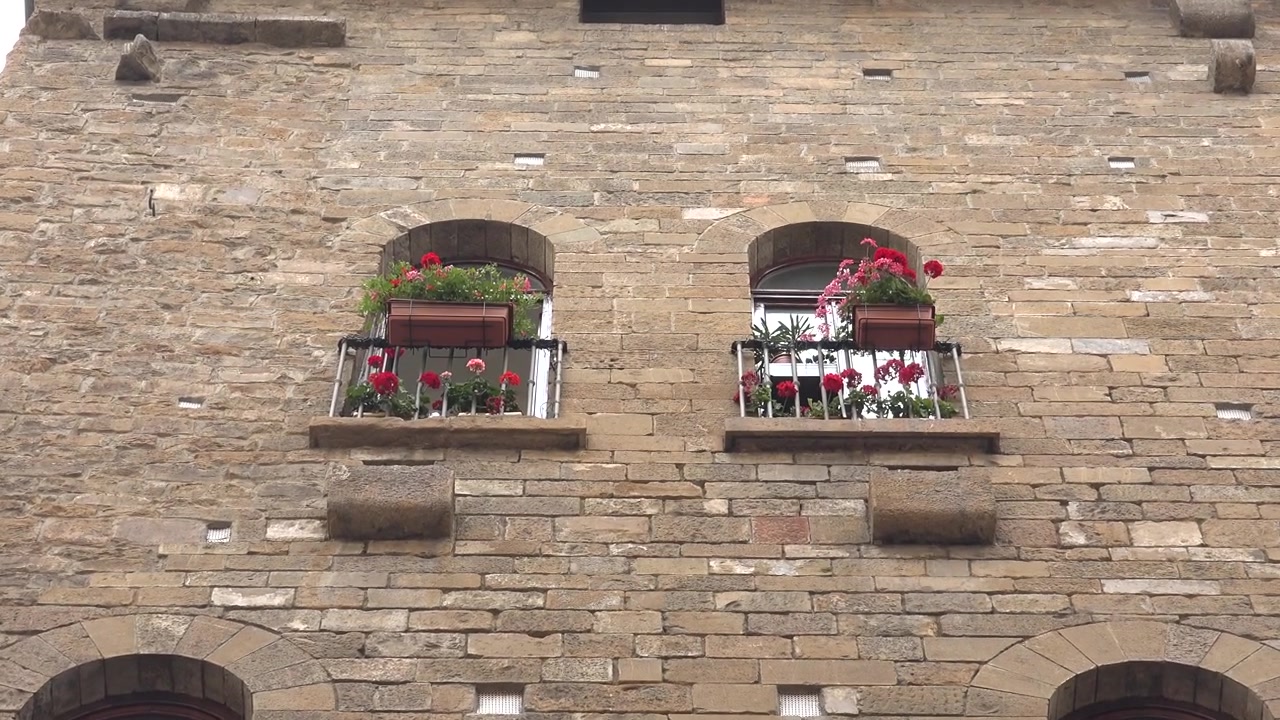 Vista dal basso di un edificio storico in pietra con fioriere