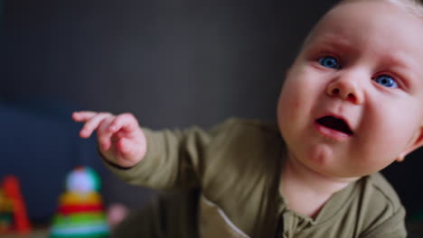small kid lies on the floor crawling to camera. emotional infant cries and smiles as he moves. close up.