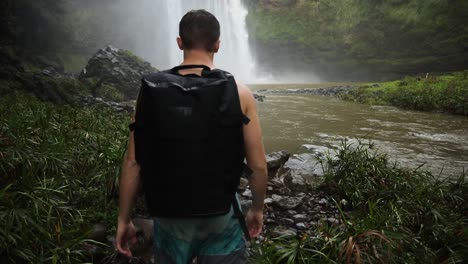 young male hiker in front of wailua falls waterfall in kauai, hawaii