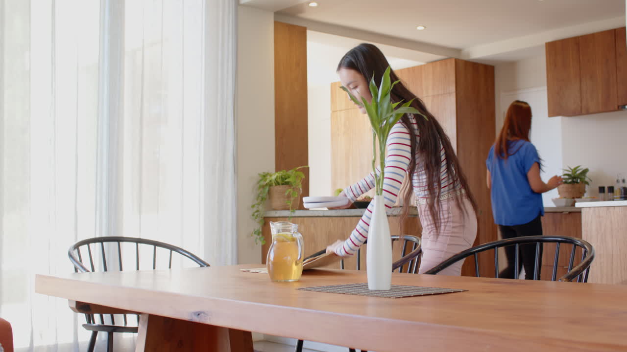 Setting table with vase and drink, young asian teenage girl preparing for meal at home