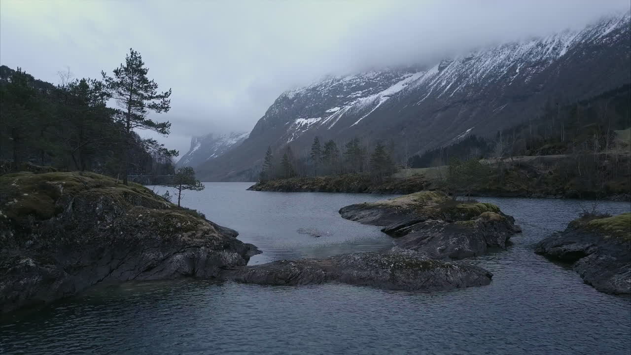 Revealing aerial shot of Norwegian wilderness, Small rocky islands in fjord covered by moss and trees, Cloudy